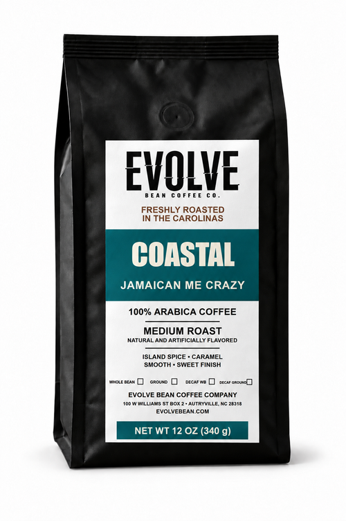 A 12 oz black bag of Evolve Bean Coffee Co. Coastal Jamaican Me Crazy medium roast coffee, featuring a white and teal label on a clean white background.